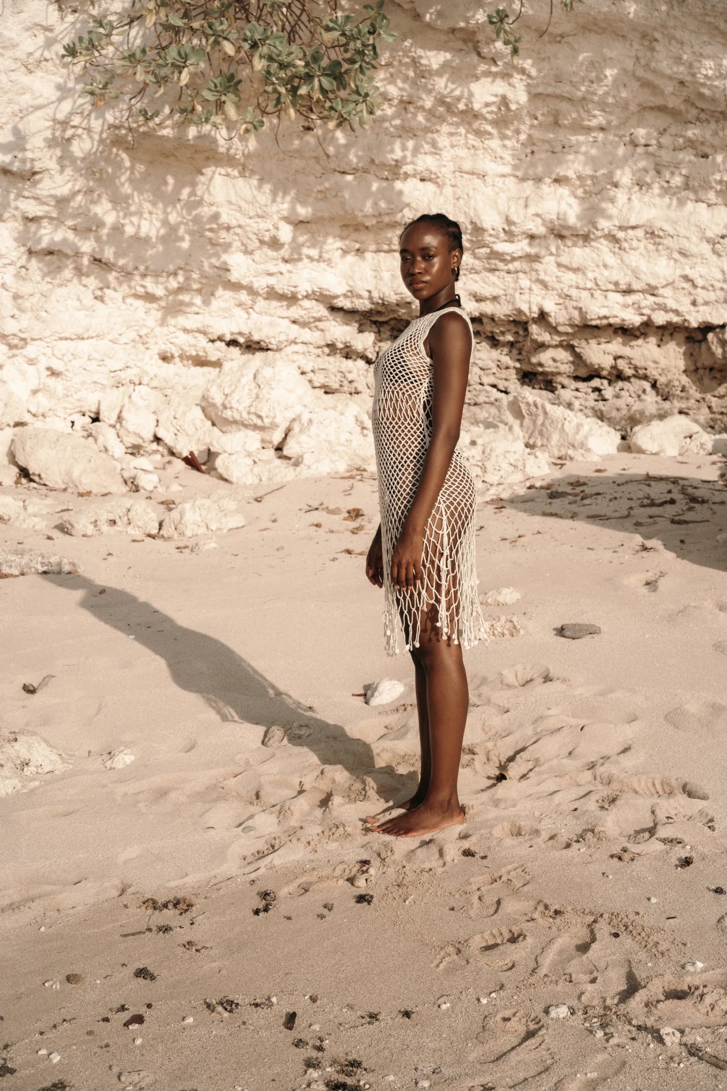 Binar Dress in Ivory - sleeveless fishnet crochet mini with dramatic fringe hem, side view | NYALA