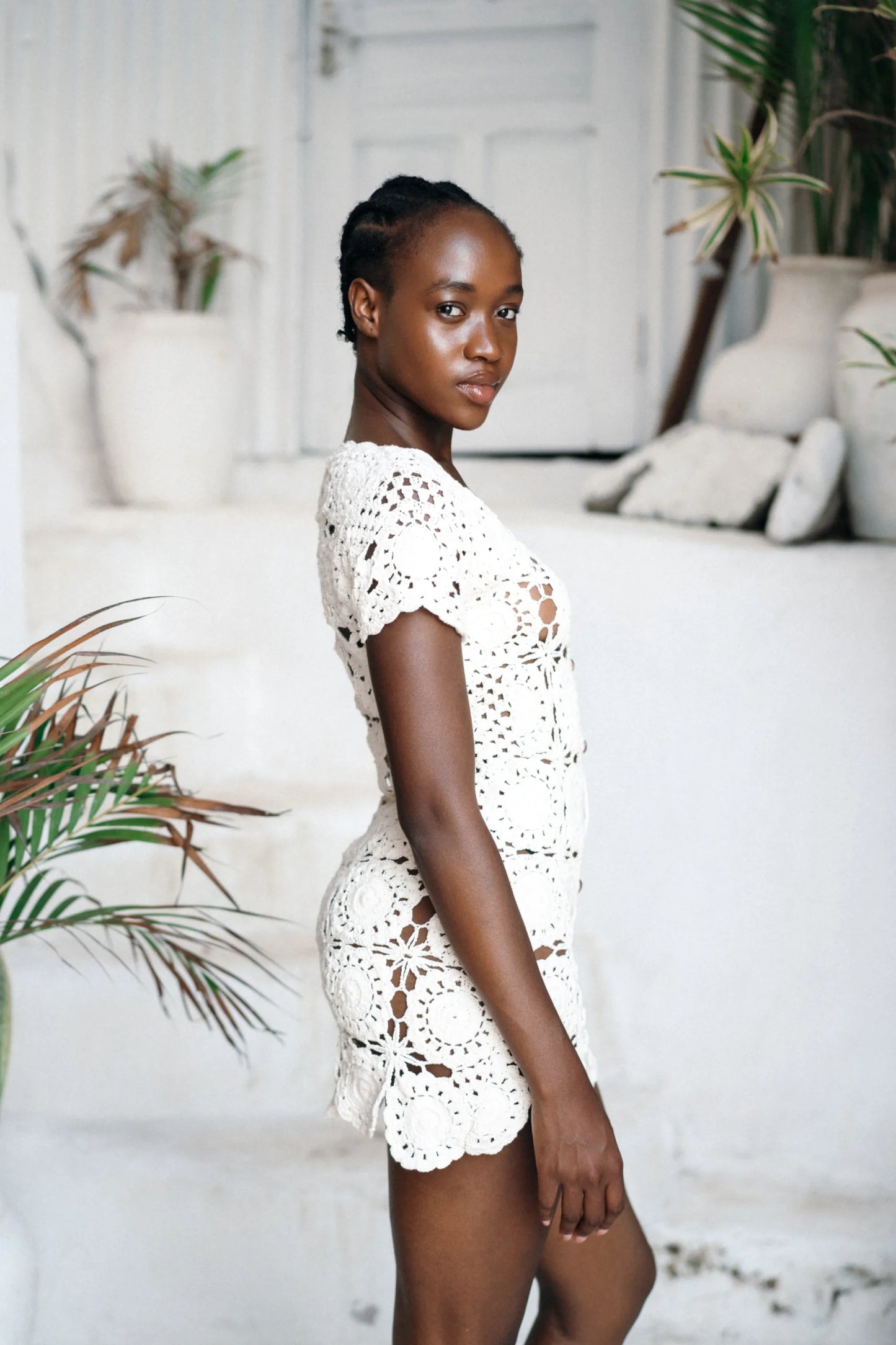 Zia Dress in Ivory - slim-fit floral crochet button-down mini with scalloped hem, side close view | NYALA